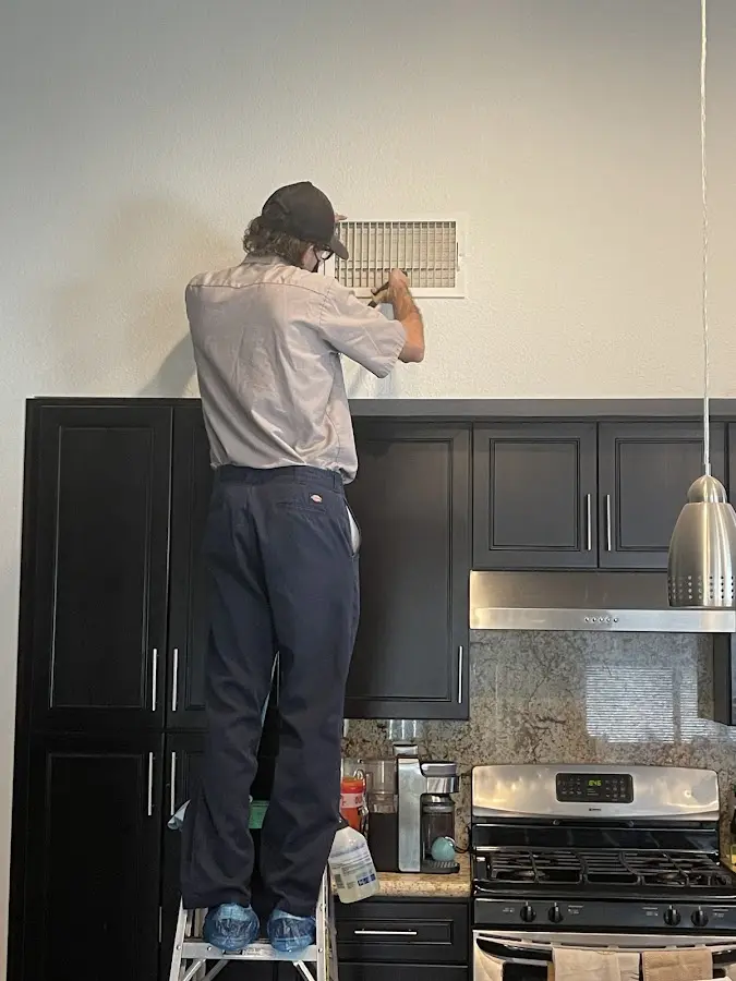 Technician inspecting an air vent during HVAC service in Eureka